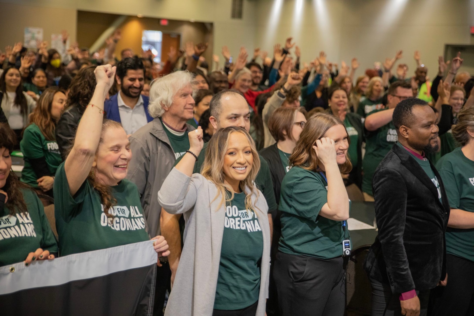 Volunteers and families wearing campaign shirts and holding banners for Food for All Oregonians during Advocacy Day.