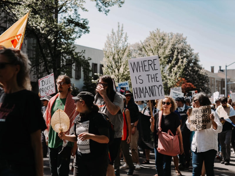 “Community members gather at a rally holding signs, including one reading ‘Where is the humanity?’ showing support for Oregonians affected by SNAP cuts.”